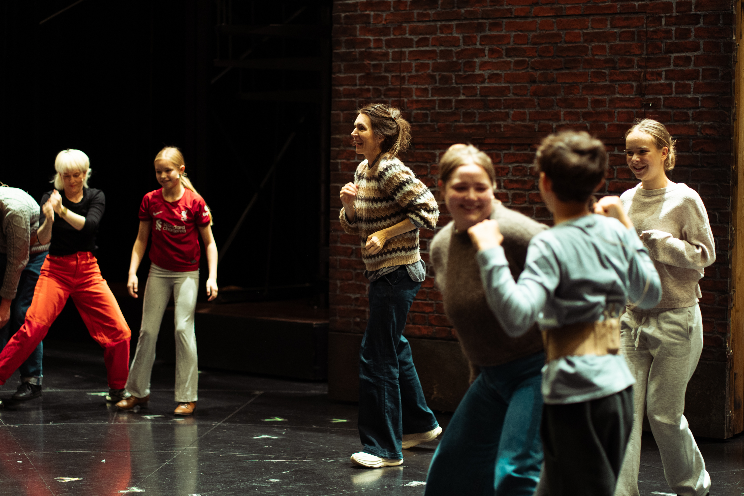 Katrine Strøm i fokus, barn og voksne leker på scenen