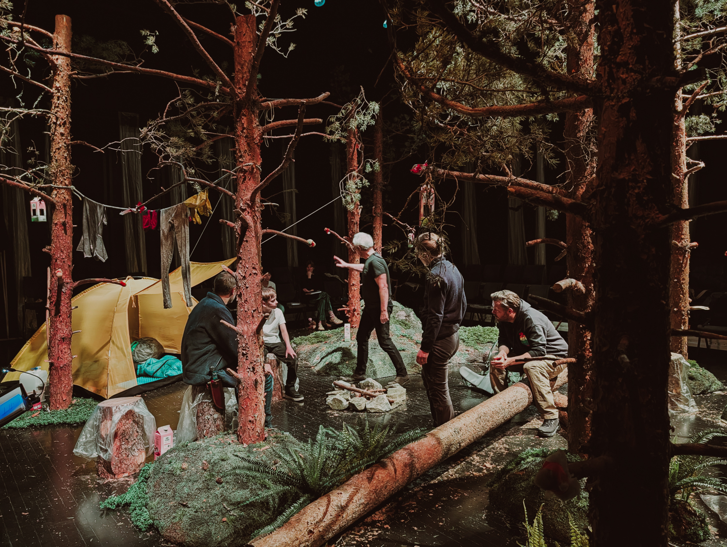 Scenografien i Doppler, en skog og et telt og skuespillere og regissør i arbeid