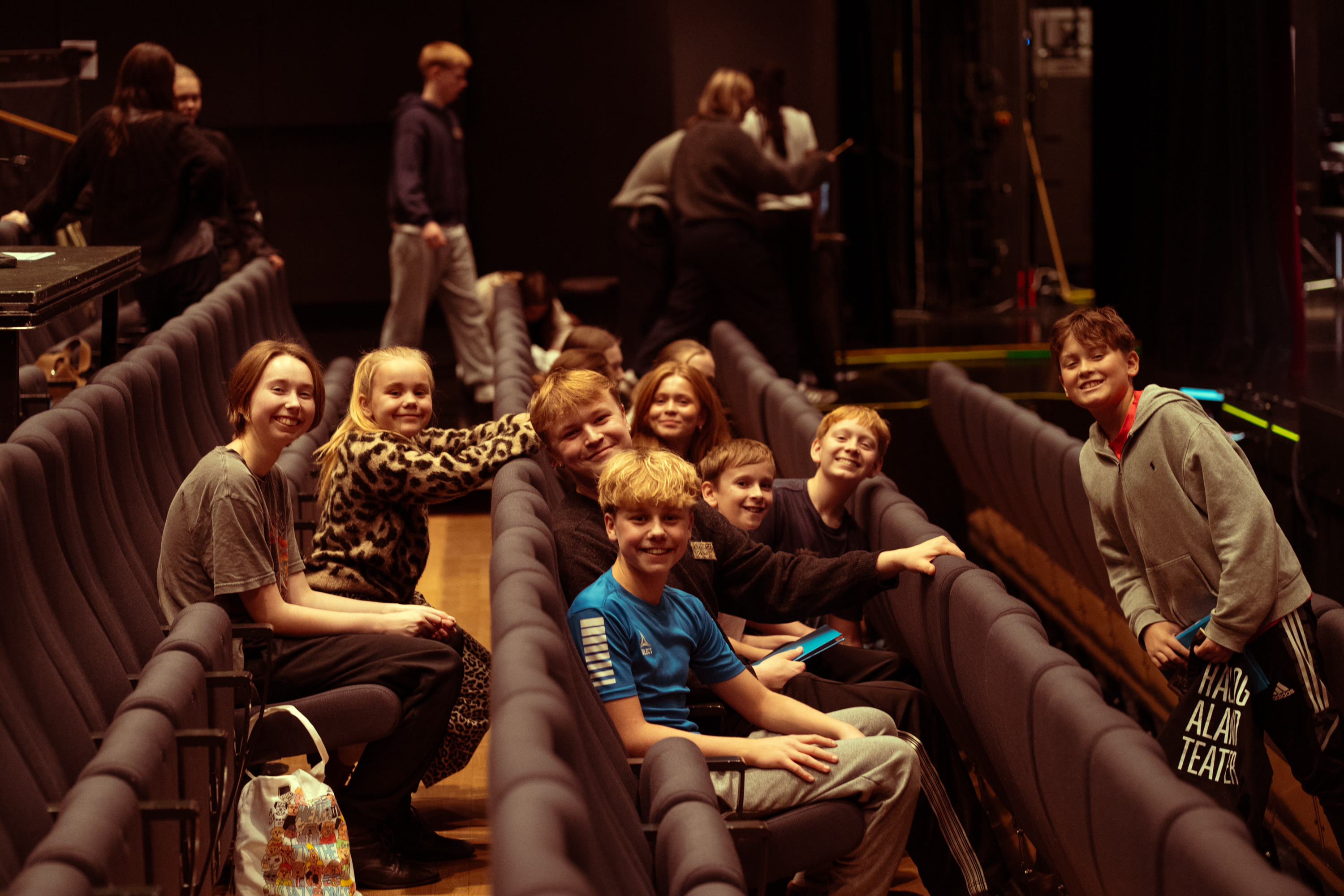 Mange barneskuespillere smilende i teatersal