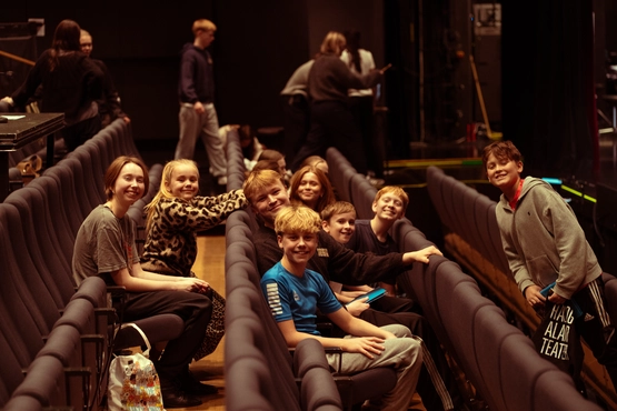 Mange barneskuespillere smilende i teatersal