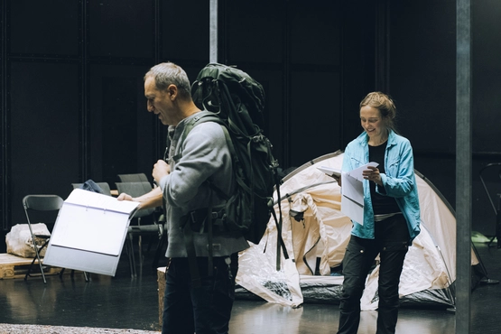 Leseprøver mann med sekk og dame foran telt